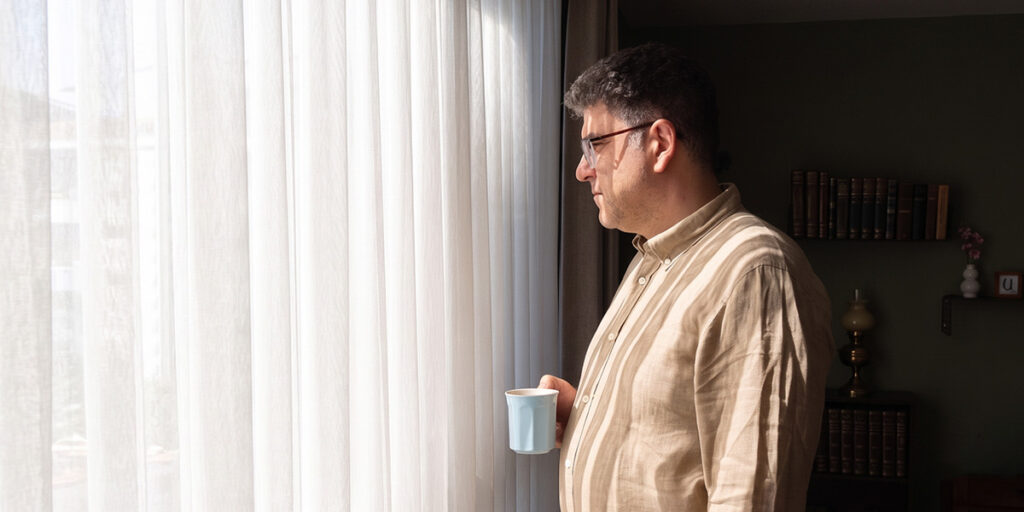build an emergency fund on a tight budget in Canada man standing by window at home natural light