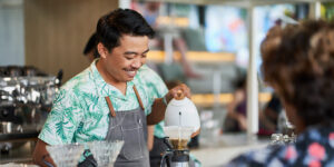 Small business owner serving coffee to a customer in a café in Canada