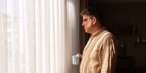 build an emergency fund on a tight budget in Canada — person standing by a window holding a coffee mug