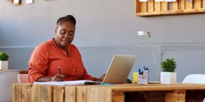 balancing short term and long term financial goals — woman reviewing a financial plan and budget beside a laptop