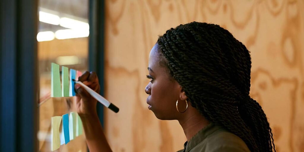 how to set financial goals — person writing goals on sticky notes during a planning session
