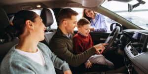 leasing vs buying a car — family sitting inside a vehicle while reviewing a car at a dealership